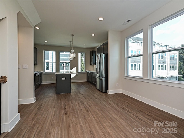 kitchen featuring dark wood finished floors, baseboards, a kitchen island, and freestanding refrigerator