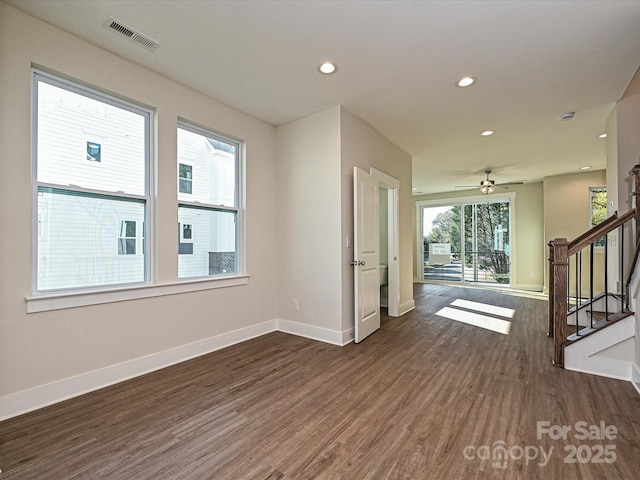 unfurnished room with stairway, baseboards, dark wood-type flooring, and visible vents