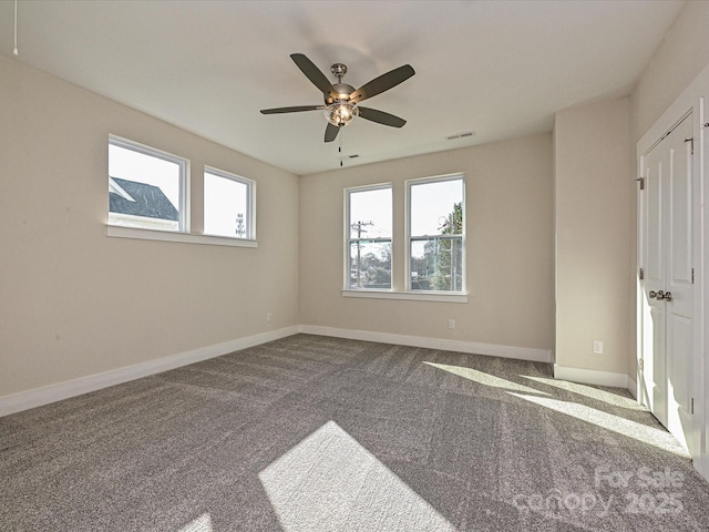 empty room featuring ceiling fan, baseboards, visible vents, and carpet