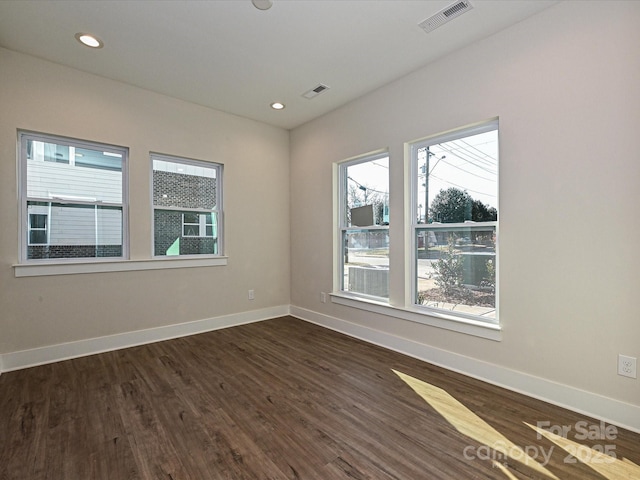 spare room with dark wood finished floors, baseboards, visible vents, and recessed lighting