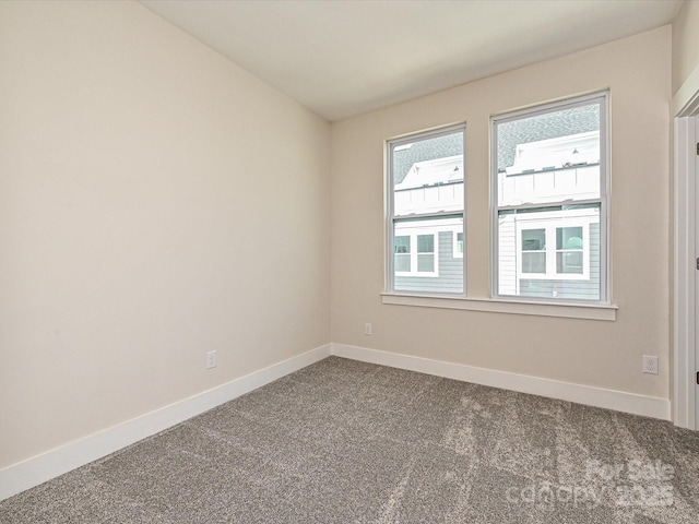unfurnished room featuring dark colored carpet and baseboards