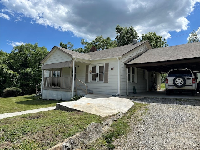 ranch-style house with a front lawn, a carport, and covered porch