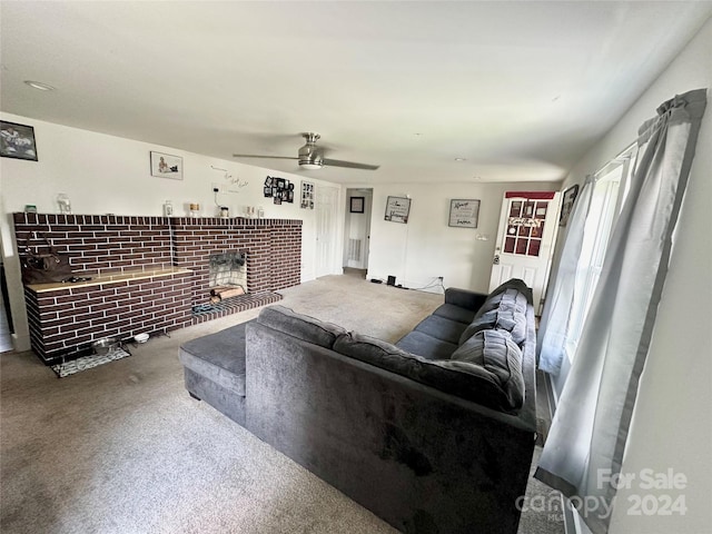 carpeted living room featuring a brick fireplace and ceiling fan