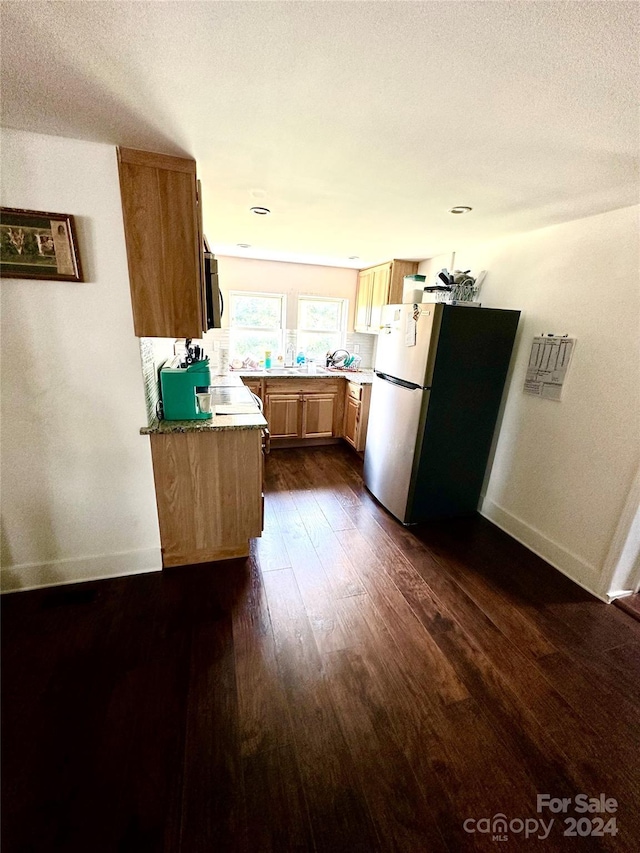 kitchen with a textured ceiling, light brown cabinets, stainless steel appliances, and dark hardwood / wood-style floors