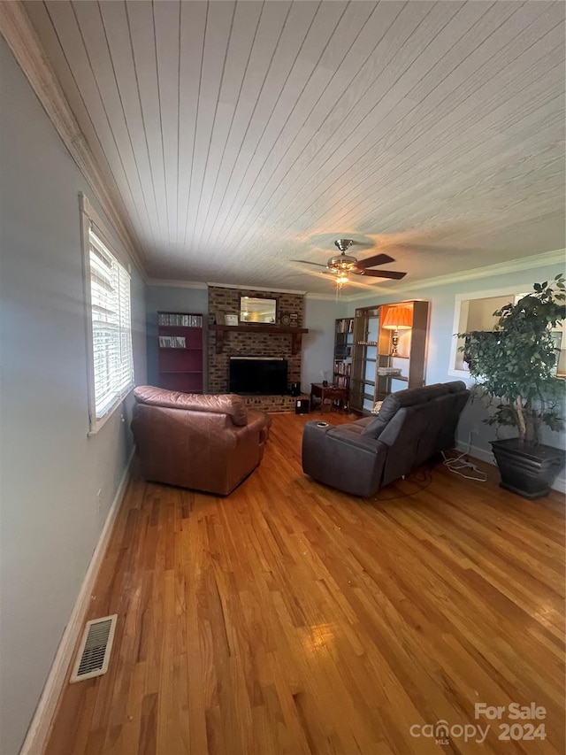 living room featuring ceiling fan, ornamental molding, a fireplace, and wood-type flooring