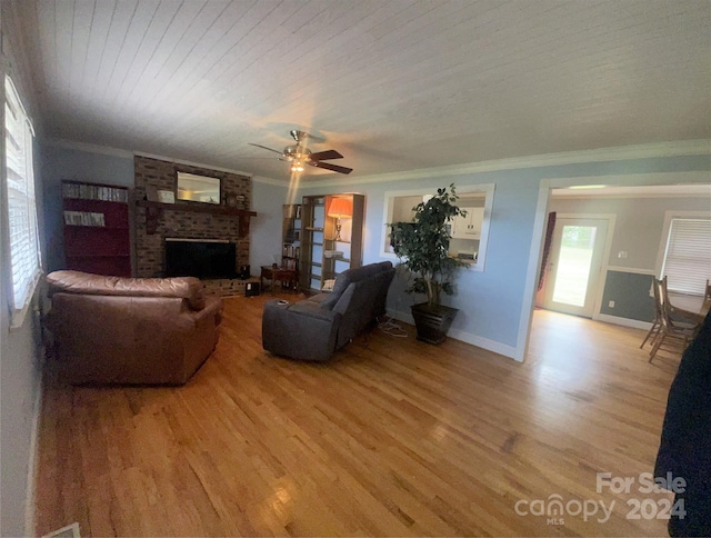 living room with hardwood / wood-style flooring, ornamental molding, a brick fireplace, and ceiling fan