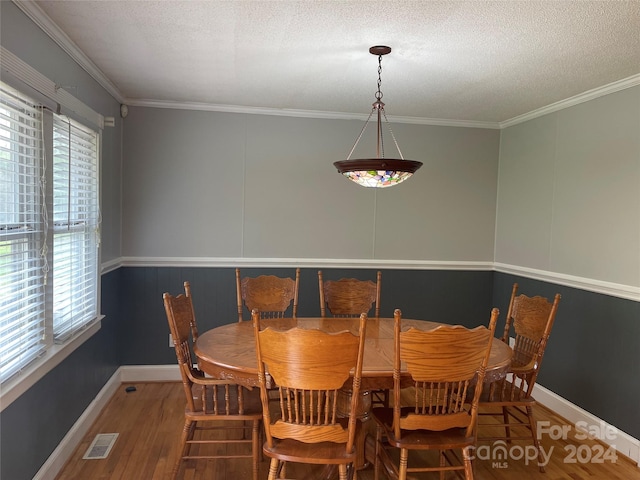 dining area with crown molding, plenty of natural light, and hardwood / wood-style floors