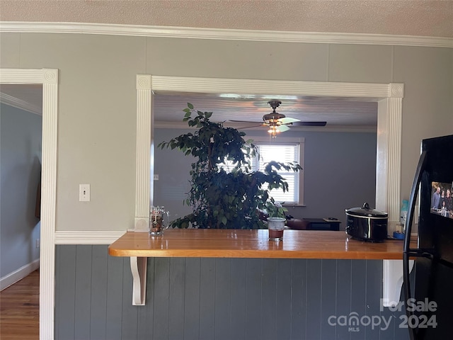 kitchen featuring black refrigerator, ceiling fan, hardwood / wood-style flooring, and crown molding