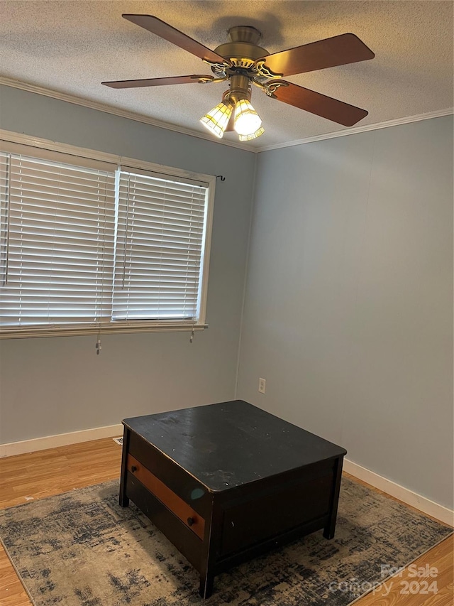 bedroom with a textured ceiling, ornamental molding, wood-type flooring, and ceiling fan