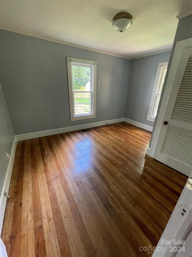 unfurnished room featuring hardwood / wood-style floors and ornamental molding