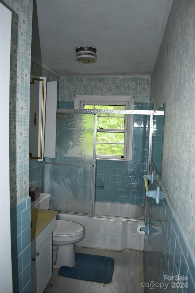 full bathroom featuring shower / bath combination with glass door, tile flooring, tile walls, vanity, and toilet