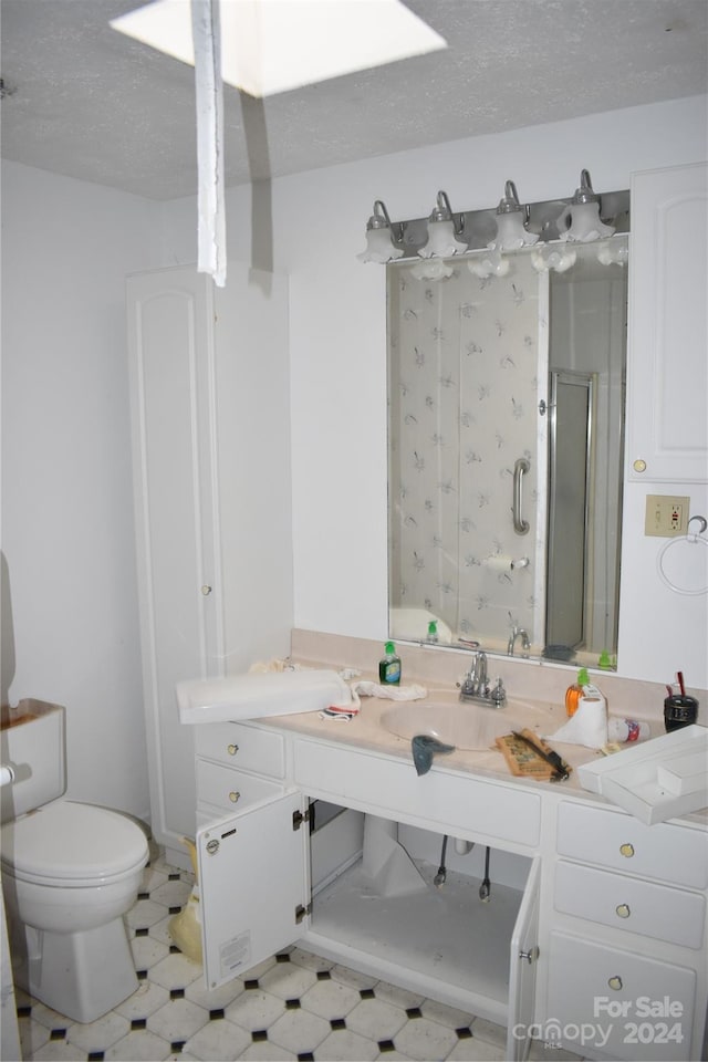 bathroom with tile flooring, vanity, toilet, and a textured ceiling