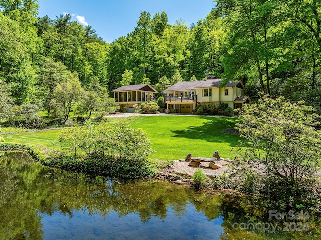 exterior space featuring a deck with water view, a fire pit, a yard, and a sunroom