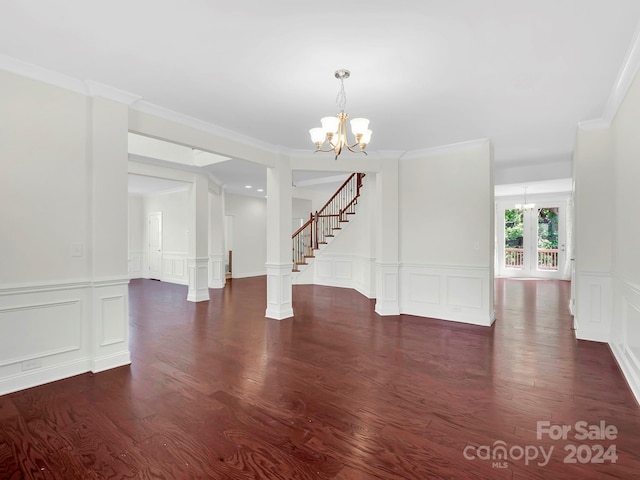 unfurnished dining area featuring ornate columns, dark hardwood / wood-style flooring, ornamental molding, and a chandelier