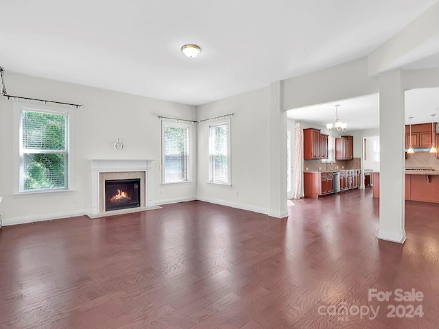 unfurnished living room featuring a chandelier, a high end fireplace, and dark hardwood / wood-style flooring