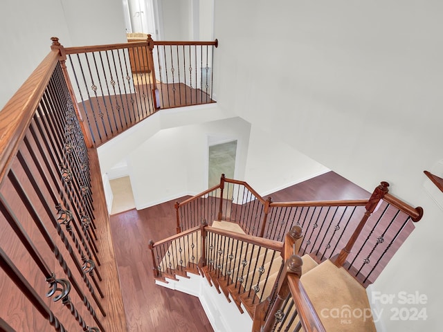 stairs with a towering ceiling and hardwood / wood-style flooring