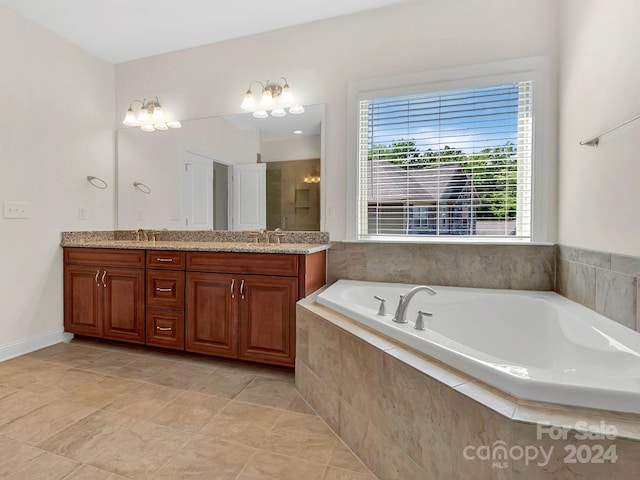 bathroom with tile floors, an inviting chandelier, tiled tub, and dual bowl vanity