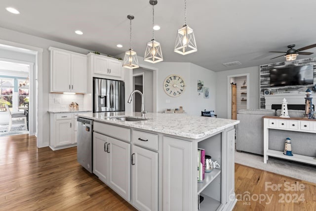 kitchen with appliances with stainless steel finishes, sink, hardwood / wood-style flooring, and white cabinetry