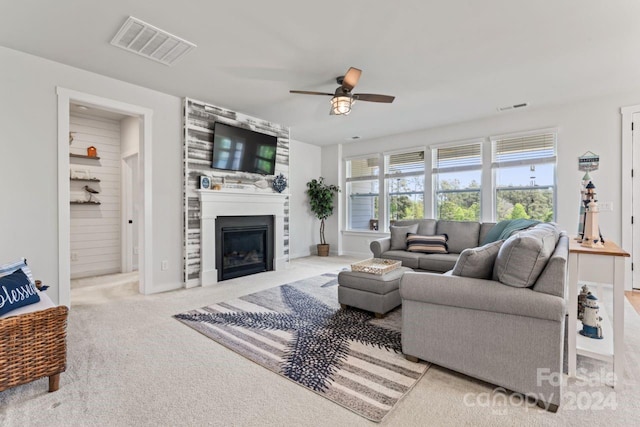 carpeted living room with a fireplace and ceiling fan