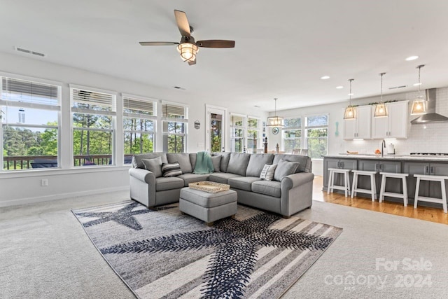 living room with sink, ceiling fan, and carpet floors