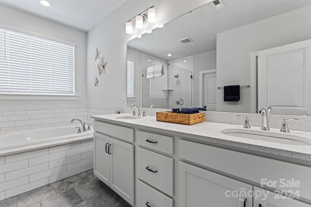 bathroom with shower with separate bathtub, vanity with extensive cabinet space, dual sinks, and tile flooring