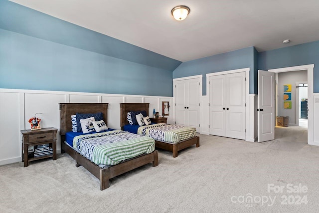 bedroom featuring multiple closets, carpet, and vaulted ceiling