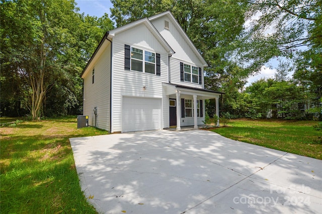 traditional home with cooling unit, a garage, concrete driveway, board and batten siding, and a front yard