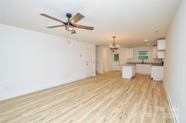 unfurnished living room with ceiling fan with notable chandelier, sink, and light hardwood / wood-style flooring