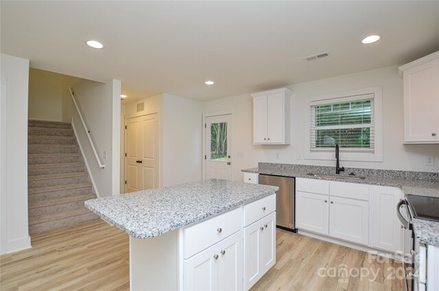 kitchen with appliances with stainless steel finishes, sink, light hardwood / wood-style flooring, and a center island