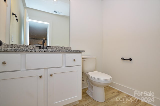 bathroom featuring toilet, hardwood / wood-style floors, and vanity