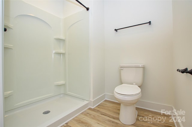 bathroom featuring a shower, toilet, and wood-type flooring