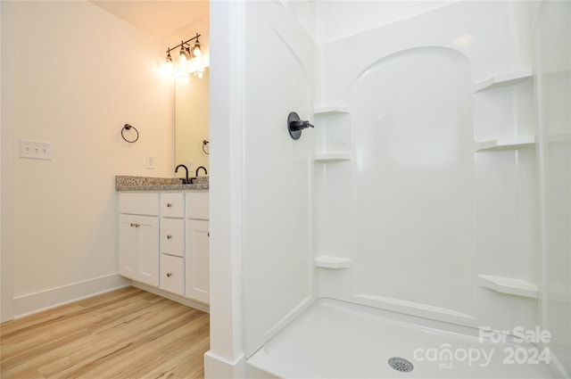 bathroom with a shower, vanity, and hardwood / wood-style floors