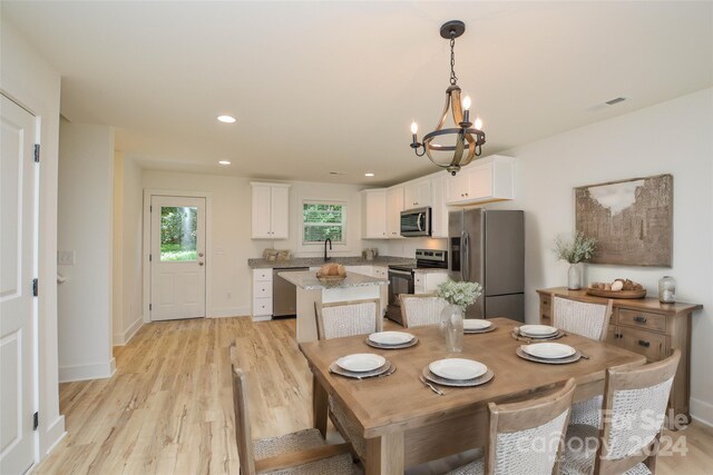 dining area featuring light wood-type flooring, sink, and a notable chandelier