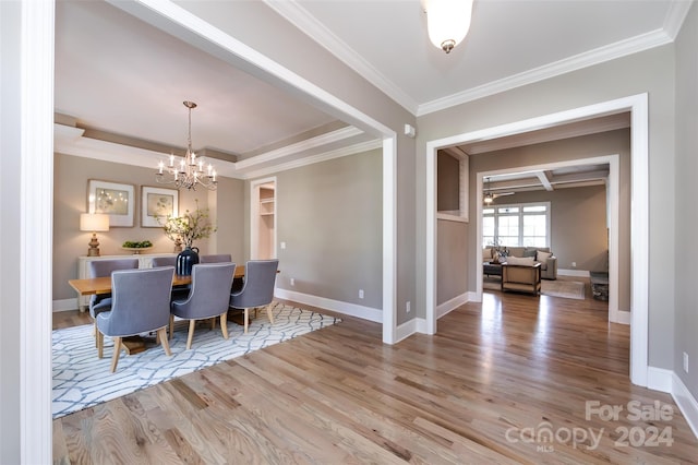 dining space with hardwood / wood-style flooring, beam ceiling, crown molding, and an inviting chandelier