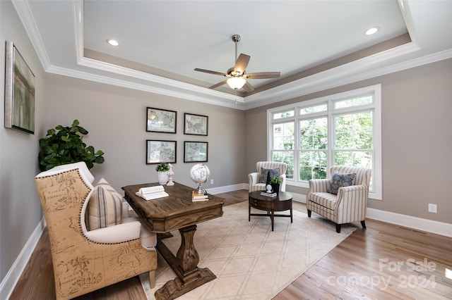 sitting room with crown molding, light hardwood / wood-style flooring, and a raised ceiling