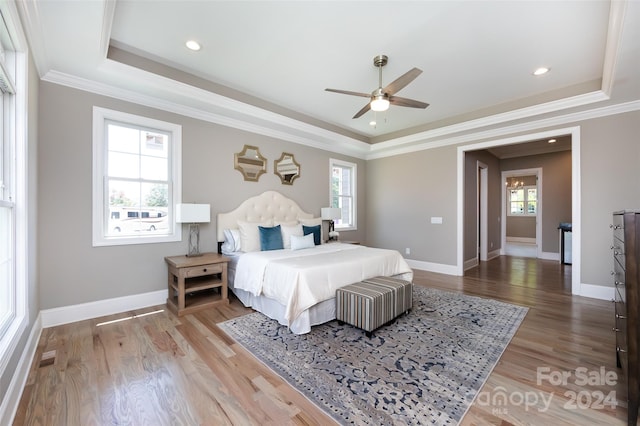 bedroom with ceiling fan, crown molding, a tray ceiling, and multiple windows