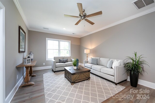 living room featuring ceiling fan, light wood-type flooring, and crown molding