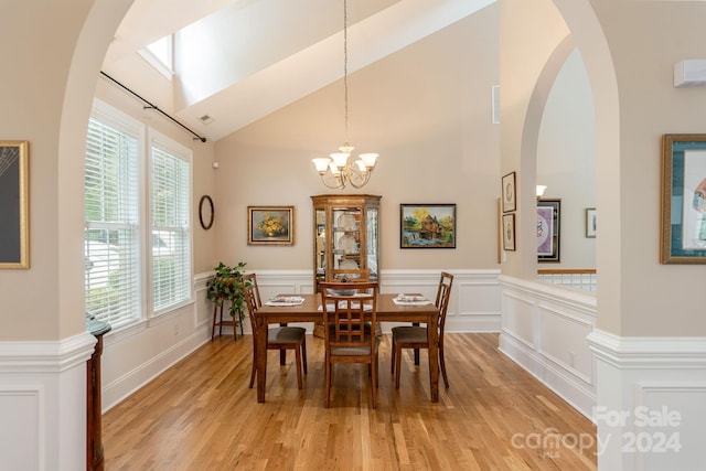 dining room with a wealth of natural light, an inviting chandelier, high vaulted ceiling, and light hardwood / wood-style floors