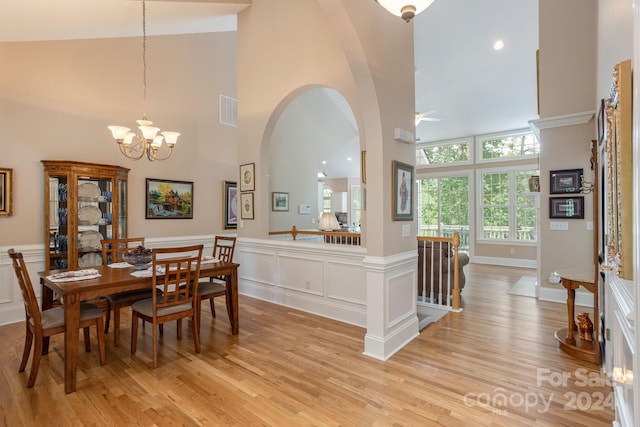 dining space with high vaulted ceiling, ceiling fan with notable chandelier, and light hardwood / wood-style floors