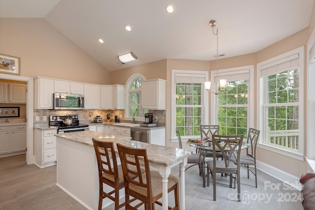 kitchen with stainless steel appliances, hanging light fixtures, a healthy amount of sunlight, and a kitchen island