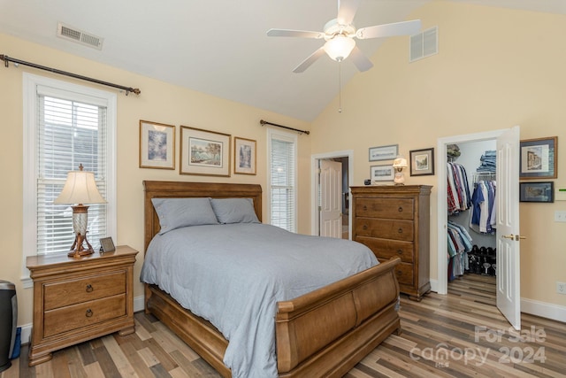 bedroom featuring ceiling fan, a closet, hardwood / wood-style floors, high vaulted ceiling, and a walk in closet