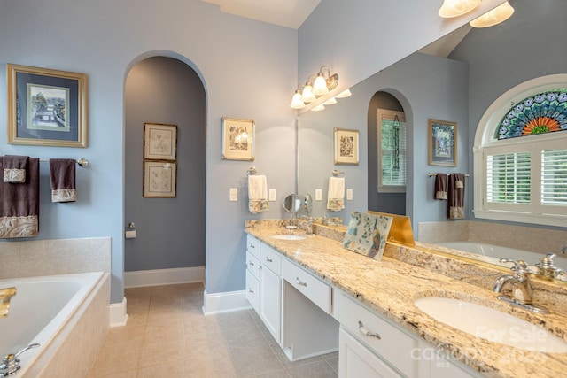 bathroom featuring dual vanity, tiled tub, and tile floors