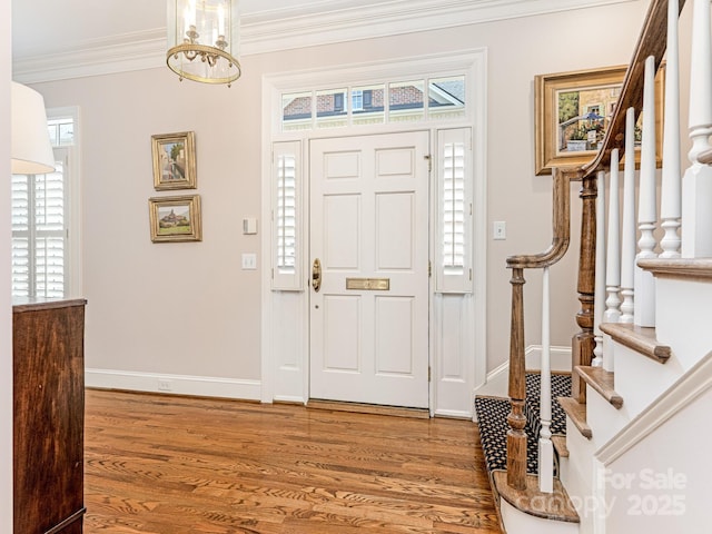 entryway with a chandelier, ornamental molding, and hardwood / wood-style floors