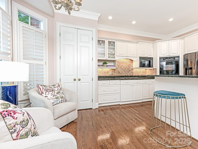 kitchen with dark wood-type flooring, backsplash, white cabinets, and black appliances