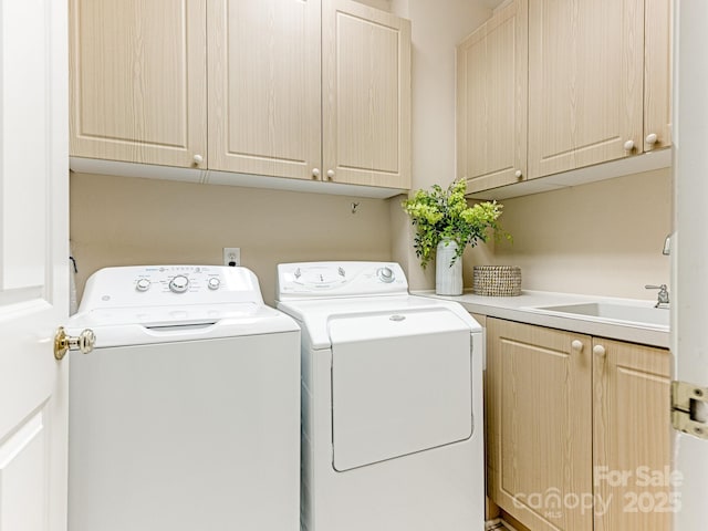 clothes washing area featuring cabinets, sink, and independent washer and dryer