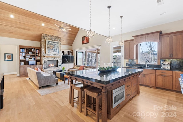 kitchen featuring a fireplace, light wood-type flooring, tasteful backsplash, wood ceiling, and a kitchen bar