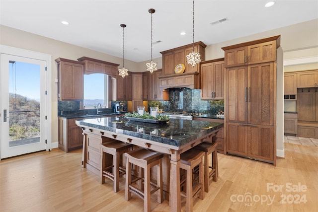 kitchen featuring plenty of natural light, light hardwood / wood-style flooring, a kitchen bar, and tasteful backsplash