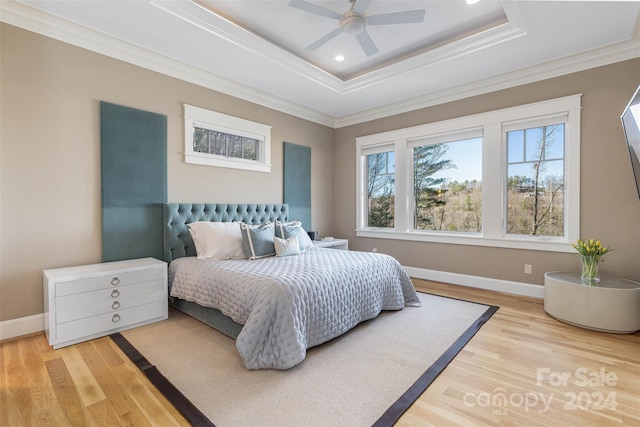 bedroom featuring ceiling fan, light hardwood / wood-style flooring, a raised ceiling, and crown molding