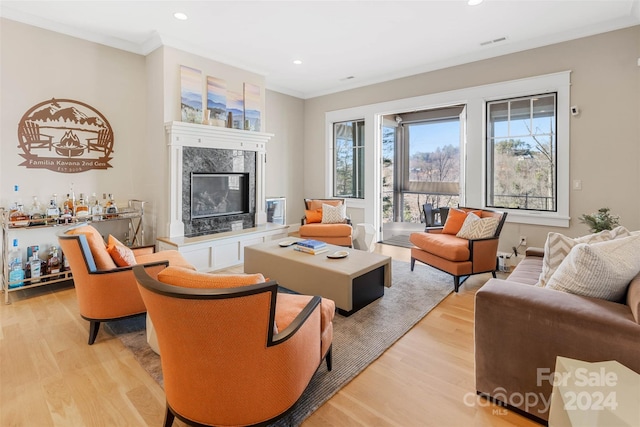 living room featuring light hardwood / wood-style floors, ornamental molding, and a fireplace