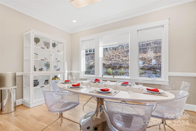 dining room with ornamental molding and light hardwood / wood-style flooring